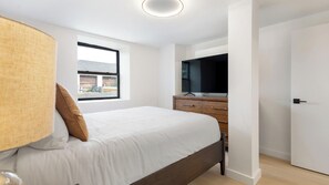Ein Schlafzimmer mit Bett, Kommode, Fernseher und Fenster.