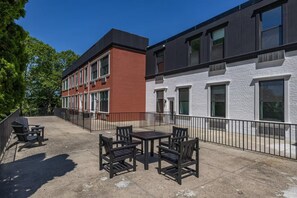 A courtyard with outdoor seating and a building with a brick facade and large windows. - Landing | Amazing 1BD, Gym (Bridgeport)