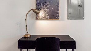 A desk with a lamp, a chair, and a framed picture on the wall. - Landing | Amazing 1BD, Gym (Bridgeport)