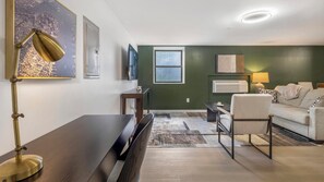 Een moderne woonkamer met een donker houten tafel, een bank, een televisie en een raam.