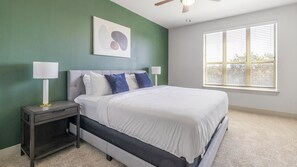 A bedroom with a bed, nightstands, a ceiling fan, a window with blinds, and a wall art piece. - Landing | Spectacular 2BD, Rooftop Lounge (Fort Worth)