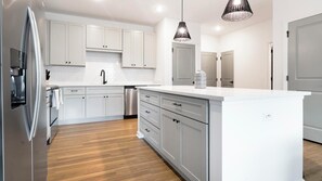 Eine moderne Küche mit weißen Schränken, Edelstahlgeräten und Holzboden.