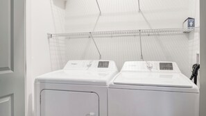 Ein Waschbereich mit zwei Frontlader-Waschmaschinen von Whirlpool und einem Metallregal darüber.