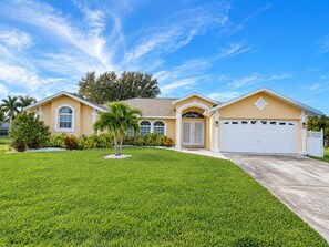 A residential house with a well-maintained lawn, a garage, and a clear blue sky. - Marker Gulf Coast Getaway (Rotonda West)