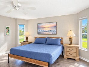 A bedroom with a bed, two bedside tables, a ceiling fan, a window, and a painting on the wall. - Marker Gulf Coast Getaway (Rotonda West)