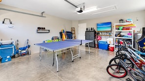 A room with a ping pong table, bicycles, and various sports equipment. - Marker Gulf Coast Getaway (Rotonda West)