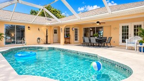 A swimming pool with a glass ceiling, a covered patio area, and a dining table with chairs. - Marker Gulf Coast Getaway (Rotonda West)
