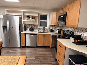 Una cocina moderna con electrodomésticos de acero inoxidable, gabinetes de madera y un salpicadero de azulejos.