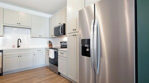 A modern kitchen with white cabinetry, stainless steel appliances, and a wooden floor. - Landing | Amazing 2BD in Heath Brook (Ocala)