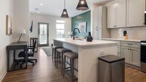 A modern kitchen with a central island, bar stools, and pendant lighting. - Landing | Spectacular 1BD in Heath Brook (Ocala)