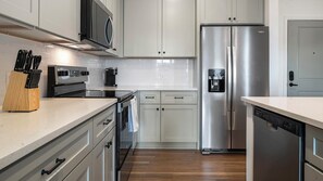A modern kitchen with stainless steel appliances, white cabinetry, and a wooden countertop. - Landing | Spectacular 1BD in Heath Brook (Ocala)