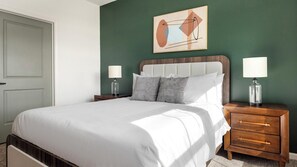 A neatly made bed with white linens, a headboard with a wooden finish, and two bedside tables with lamps. - Landing | Spectacular 1BD in Heath Brook (Ocala)