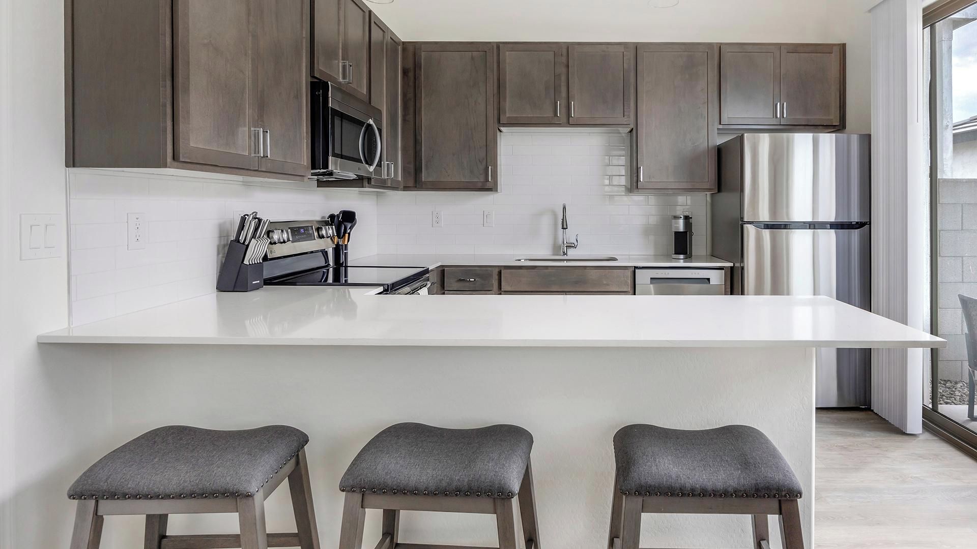 A modern kitchen with a large island, stainless steel appliances, and bar stools.