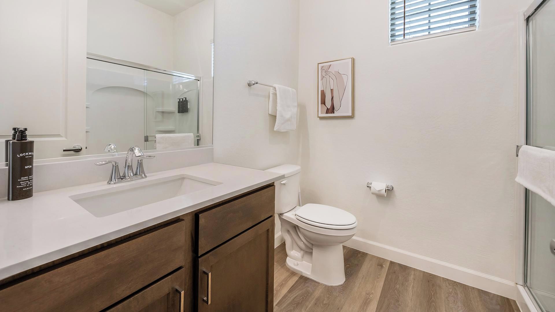 Un baño moderno con un espejo grande, un lavabo, un inodoro y una zona de ducha.