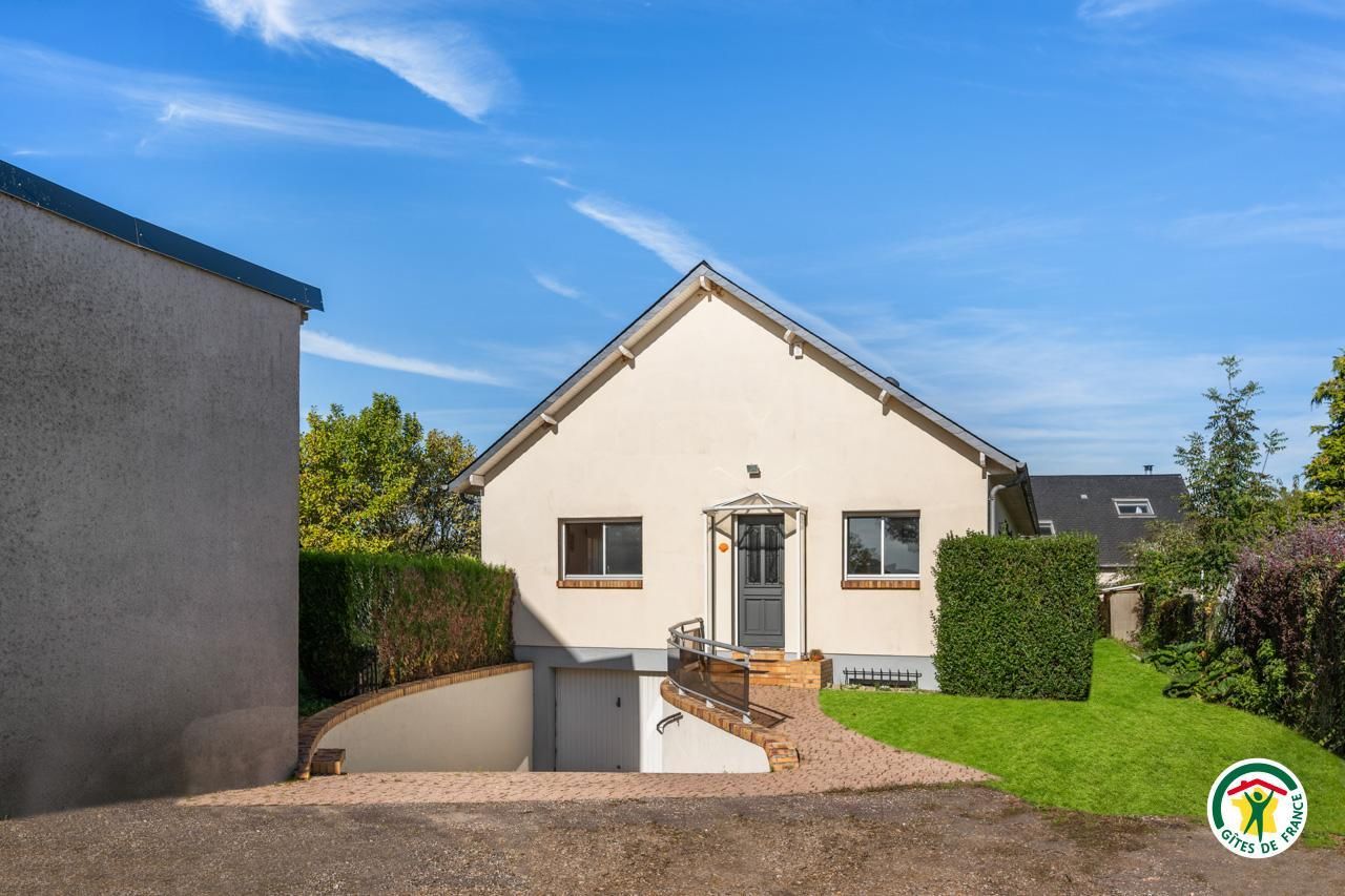 Ein eingeschossiges Haus mit Veranda, einer kleinen Auffahrt und einem gepflegten Rasen.