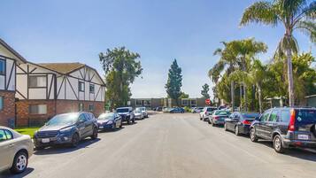 A street lined with parked cars and residential buildings.