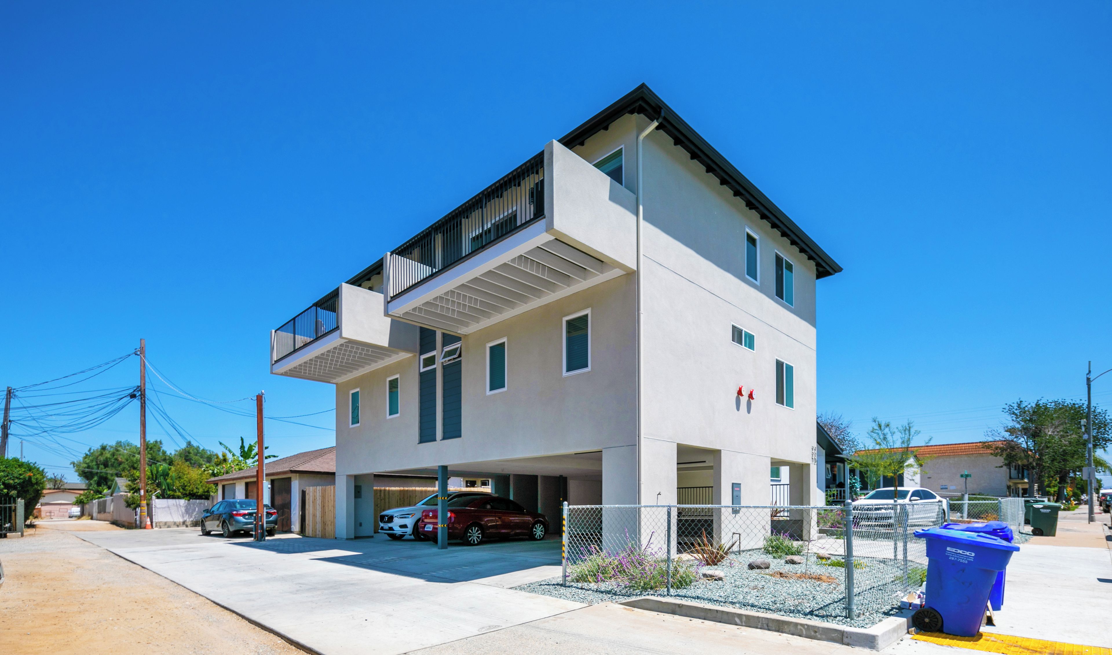 Un bâtiment moderne à deux étages, doté d’un toit plat, d’un espace de stationnement couvert et d’un jardin clos.
