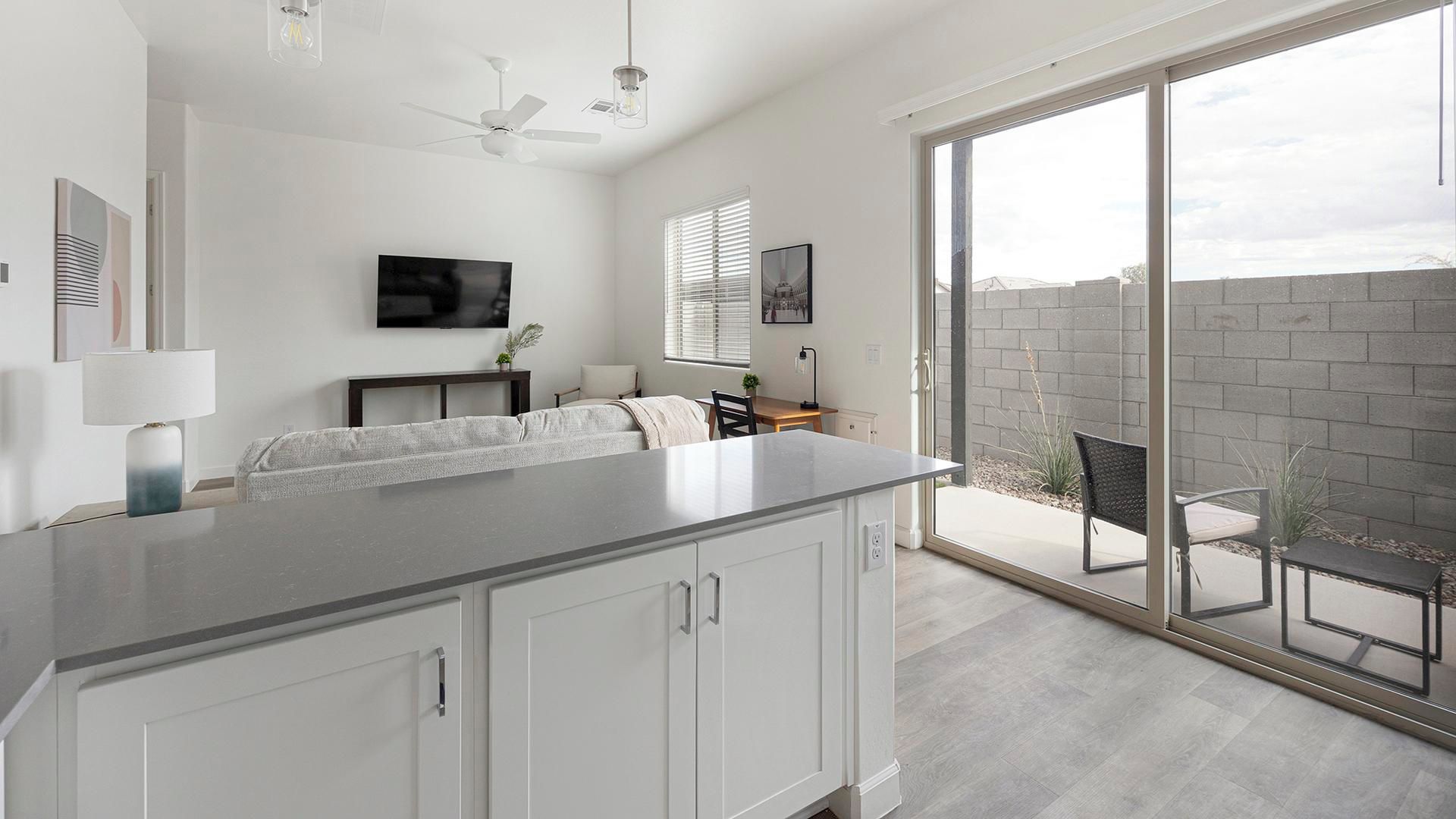 A modern kitchen with a large island, a dining area, and a sliding glass door leading to an outdoor patio.