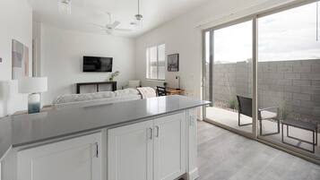 A modern kitchen with a large island, a dining area, and a sliding glass door leading to an outdoor patio.