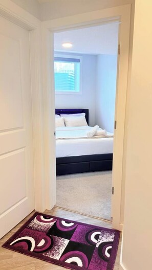 A bedroom with a bed, a window, and a door. - Cozy Queen Suite|Private Basement (Calgary)