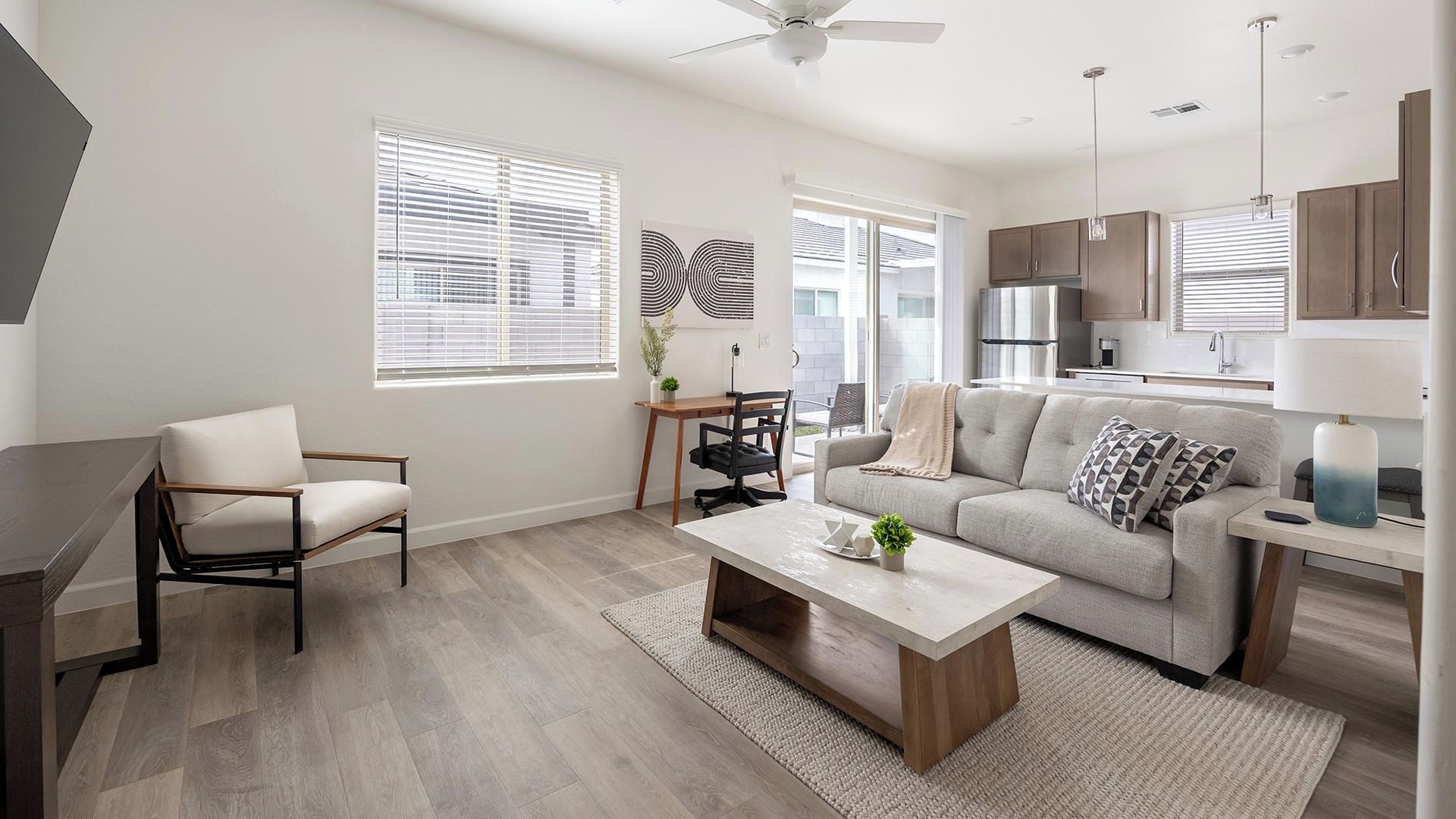 A modern living room with a sofa, coffee table, and a desk with a chair.