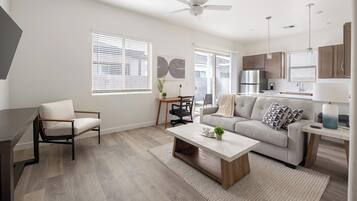 A modern living room with a sofa, coffee table, and a desk with a chair.
