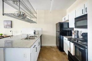 Una cucina con piano di lavoro in granito, elettrodomestici in acciaio inossidabile e mobili bianchi.