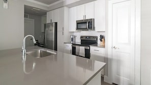A modern kitchen with stainless steel appliances, a built-in oven, and a microwave. - Landing | Stunning 1BD, Game Room, Gym (Houston)