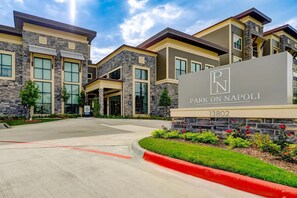 A modern building with a stone facade, large windows, and a sign reading 'Park on Napoli'. - Landing | Beautiful 1BD, Gym, Game Room (Houston)