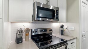 A modern kitchen with a stainless steel microwave, oven, and kettle. - Landing | Beautiful 1BD, Gym, Game Room (Houston)