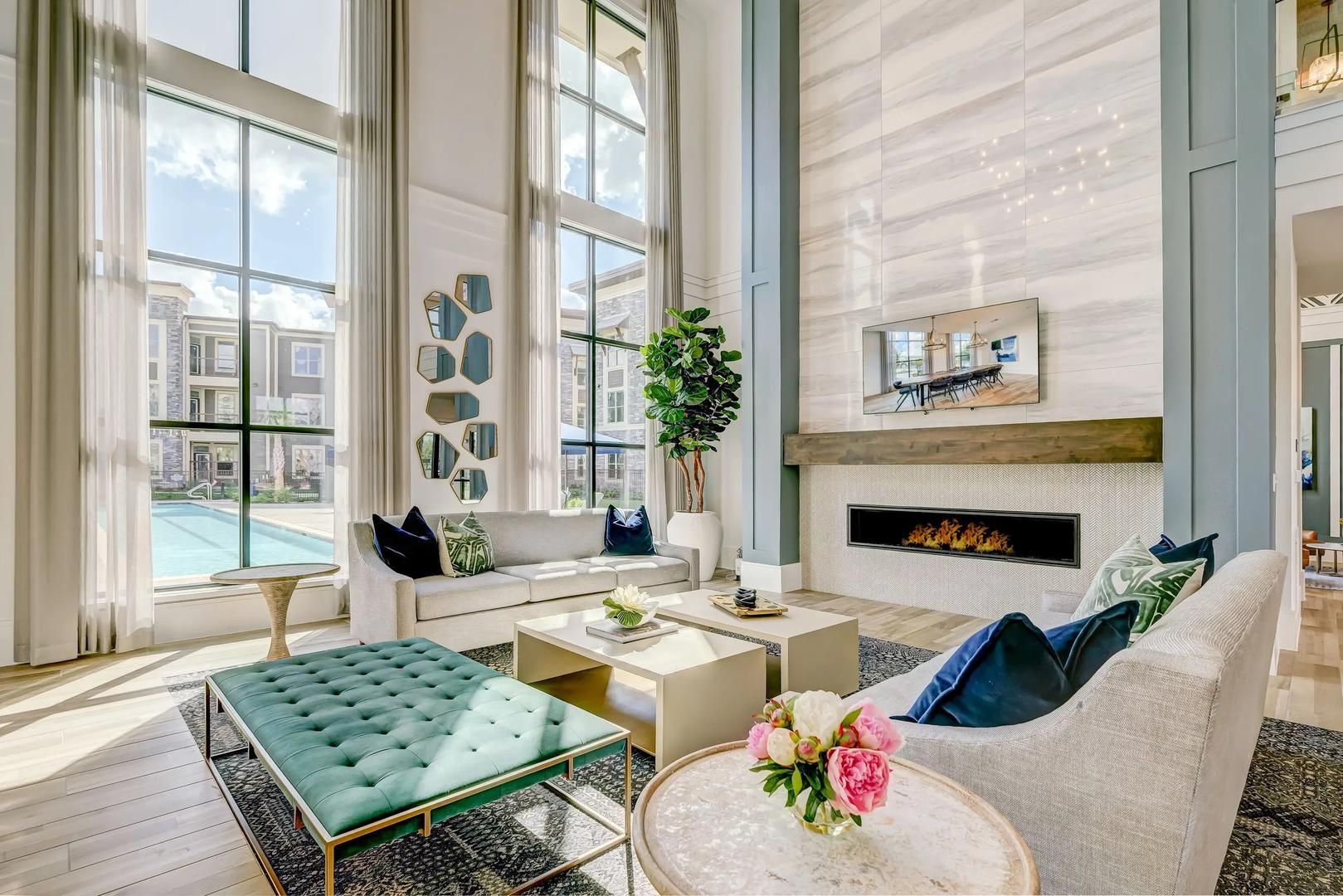 A spacious living room with a fireplace, large windows, and a view of a swimming pool.