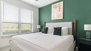 Een slaapkamer met een bed, twee bedlampen, een nachtkastje en een raam met jaloezieën.