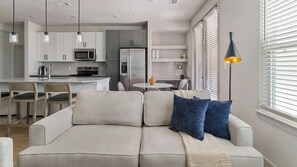 Ein modernes Wohnzimmer mit einer Couch, einem Couchtisch und einem Essbereich mit Stühlen und einem Tisch.