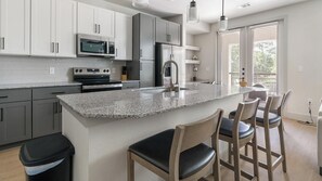 Eine moderne Küche mit Granit Arbeitsplatten, Edelstahlgeräten und Barhocker.