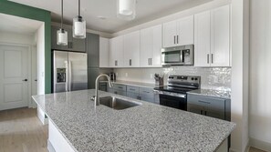 A modern kitchen with granite countertops, stainless steel appliances, and white cabinetry. - Landing | Beautiful 2BD in Deerbrook (Houston)