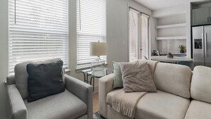 A modern living room with a sofa, a glass coffee table, and a lamp. - Landing | Spectacular 1BD in Deerbrook (Houston)