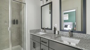 Un bagno con due lavandini, uno specchio grande e una cabina doccia.