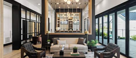 A modern living room with a sofa, two armchairs, a coffee table, and a large window with a view.
