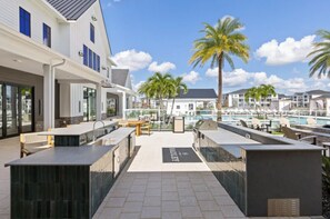 A resort with outdoor seating, a pool, and a view of the marina. - Landing | Incredible 2BD, Gym, Game Room (Cape Coral)