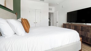 Ein Schlafzimmer mit einem großen Bett, einem Fernseher auf einer Holzkommode und einem Kleiderschrank.