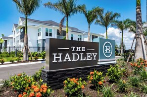 En skylt med texten ”The Hadley”, med en modern byggnad i bakgrunden.