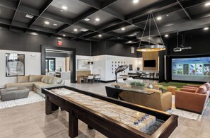 A modern interior with a billiards table, seating area, and a projection screen. - Landing | Stylish 1BD, Gym, Game Room (Cape Coral)