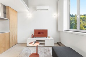 A modern, minimalist room with a television, a small table, and a sofa. - GuestReady-Rou27-G (Porto)
