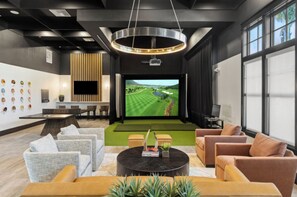 A modern lounge area with a large screen, comfortable seating, and a stylish ceiling design. - Landing | Spectacular 1BD, Gym, Game Room (Cape Coral)