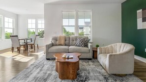 Una sala moderna con sofá, sillón, mesa de centro y comedor.
