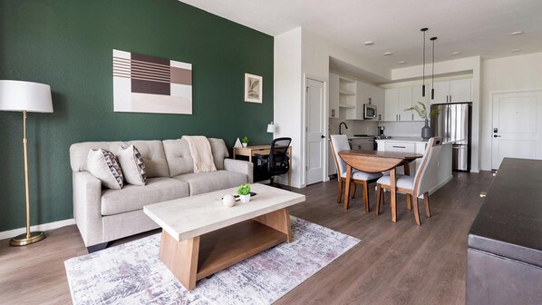 A modern living room with a sofa, coffee table, and dining area. - Landing | Modern 1BD in East Naples (Naples)