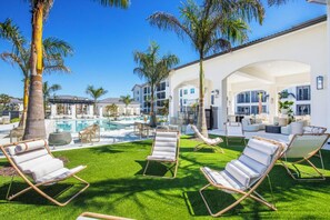 A pool area with lounge chairs and a building with multiple balconies. - Landing | Modern 1BD in East Naples (Naples)