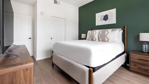 A bedroom with a bed, bedside tables, a desk, and a green wall. - Landing | Modern 1BD in East Naples (Naples)