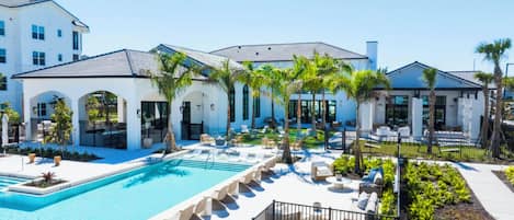 Un resort con piscina, sillas de descanso, palmeras y un edificio grande con múltiples ventanas.