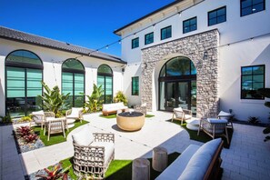 A modern outdoor patio with seating, a fire pit, and a stone wall. - Landing | Amazing 2BD in East Naples (Naples)